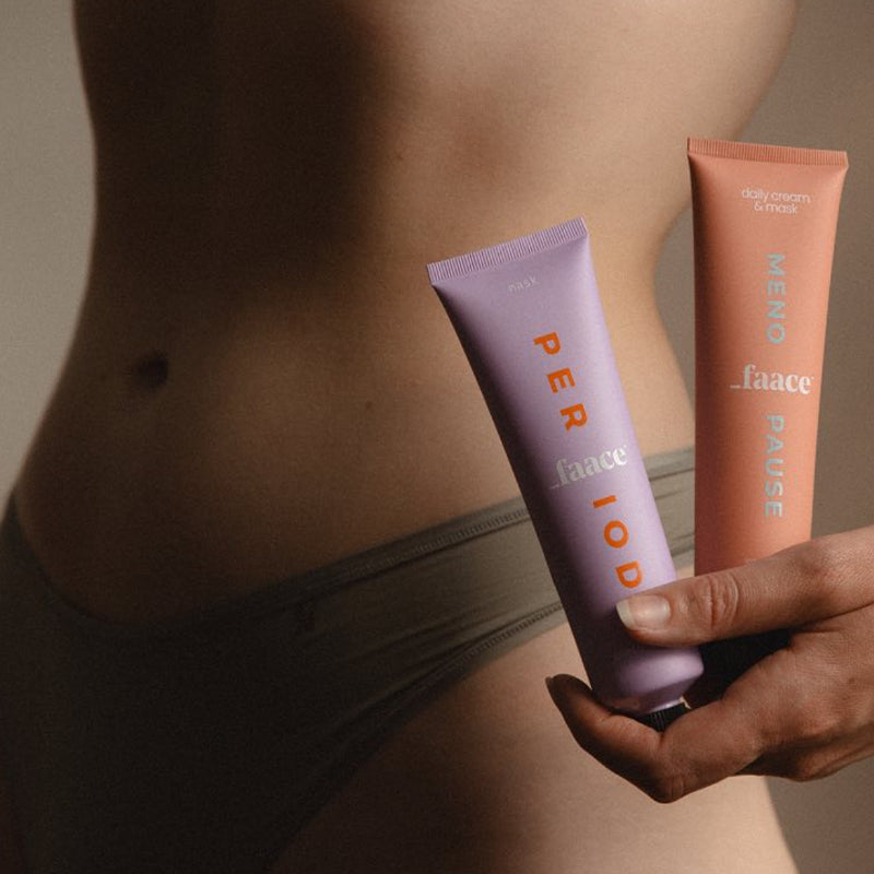 Close-up of a torso holding skincare products against a neutral background.